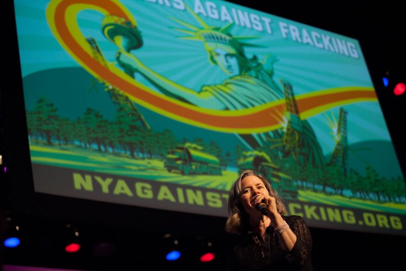 Natalie Merchant standing in front of New Yorkers Against Fracking sign